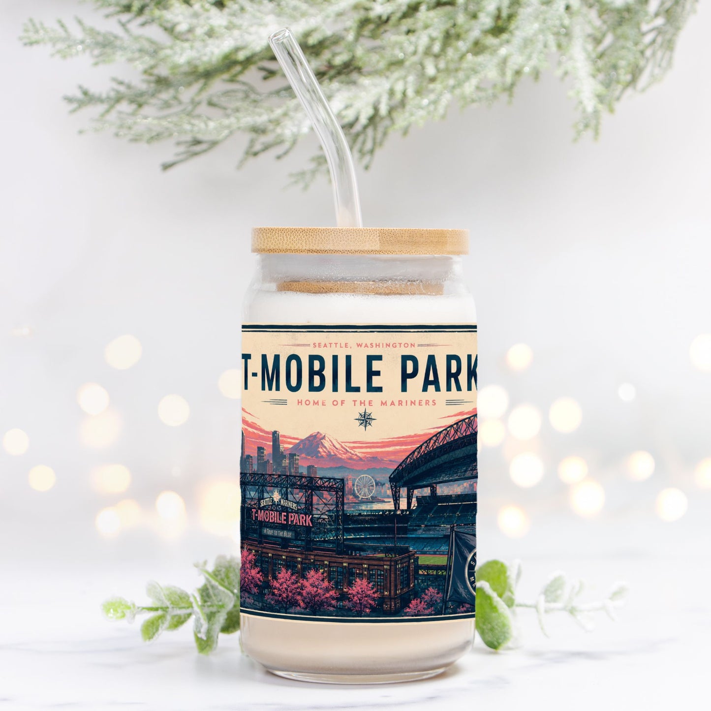 Drinking Glass with a lid and straw, featuring 'T-Mobile Park' design, on a white background with blurred lights and greenery.
