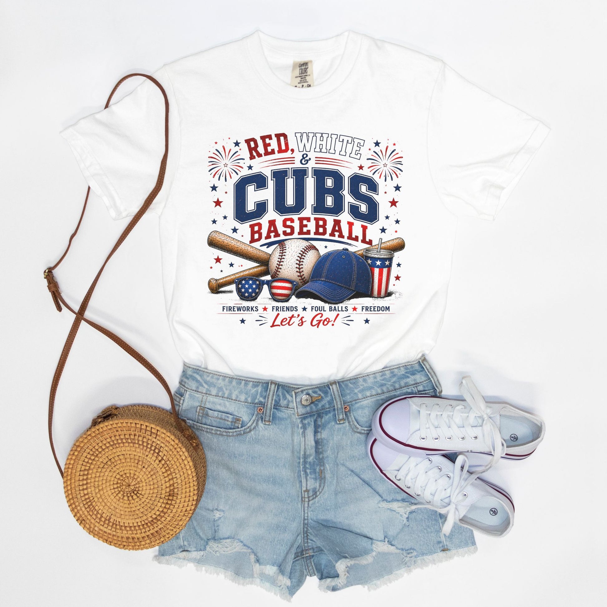 White t-shirt with 'Red, White & Cubs Baseball' design, denim shorts, white sneakers, and a woven bag on a white background.